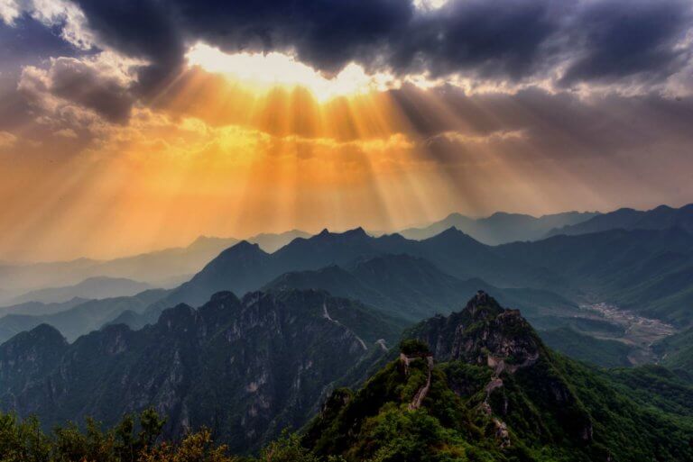 Ciel nuageux d'où filtre un rayon de soleil qui éclaire le sommet des montagnes